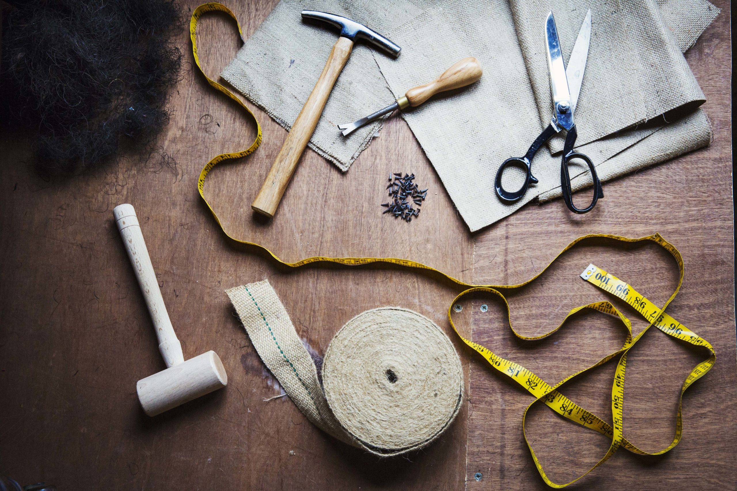 Upholstery workshop. Overhead view of hand tools, hammer, tape, tape measure and scissors. ,Watlington ,England
